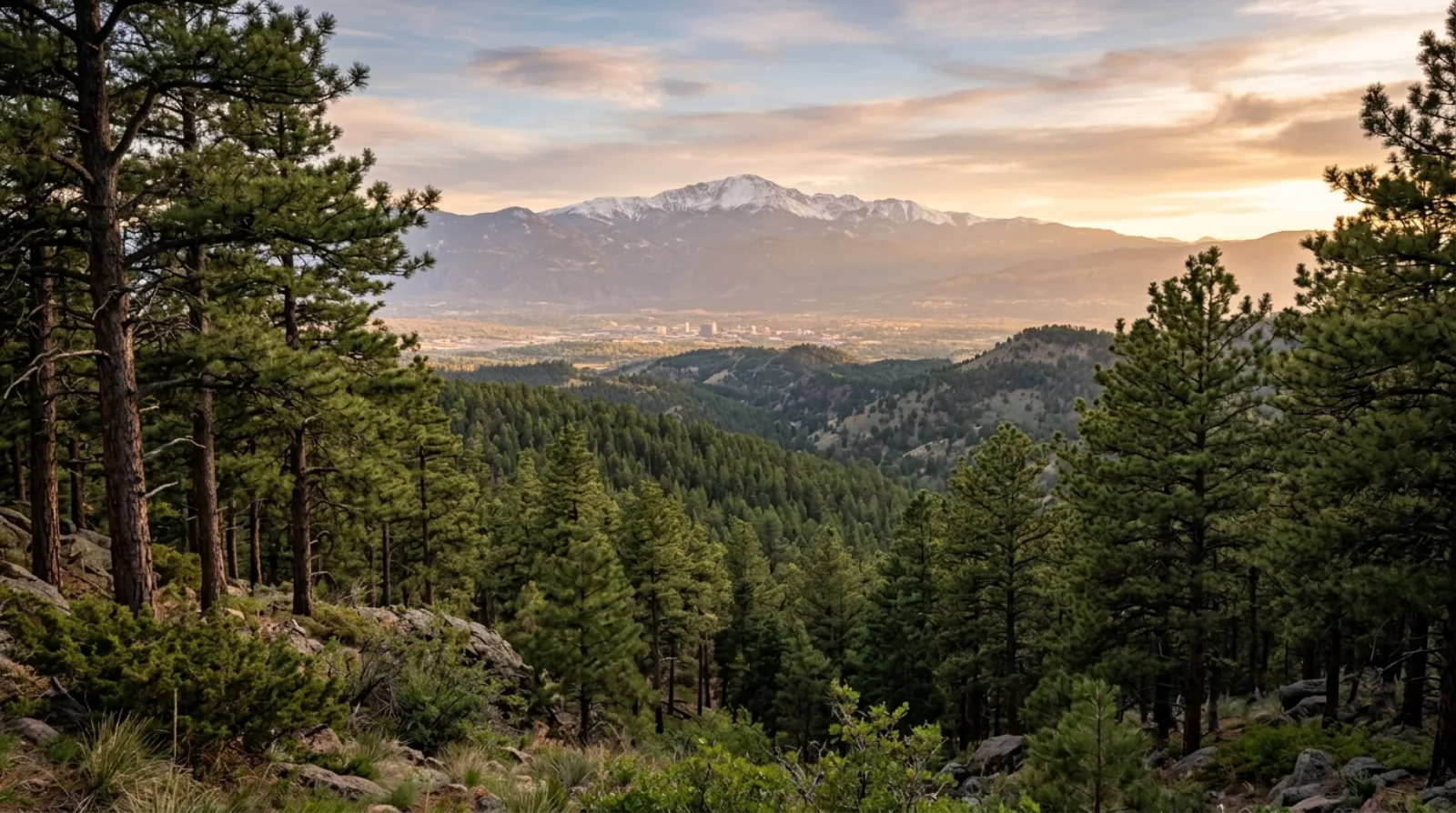 Downtown Colorado Springs at golden hour with snow-capped Pikes Peak rising behind the city